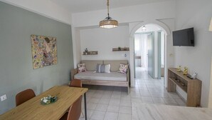 A modern living space with a dining area, sofa, TV, and artwork. - Forest View Apartment 1 by RentalsPro (Fourka)