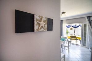 Ein Zimmer mit einem großen Fenster, einem Essbereich mit Stühlen und einem Tisch sowie einer Wand mit einem Kunstwerk von einem Seestern.