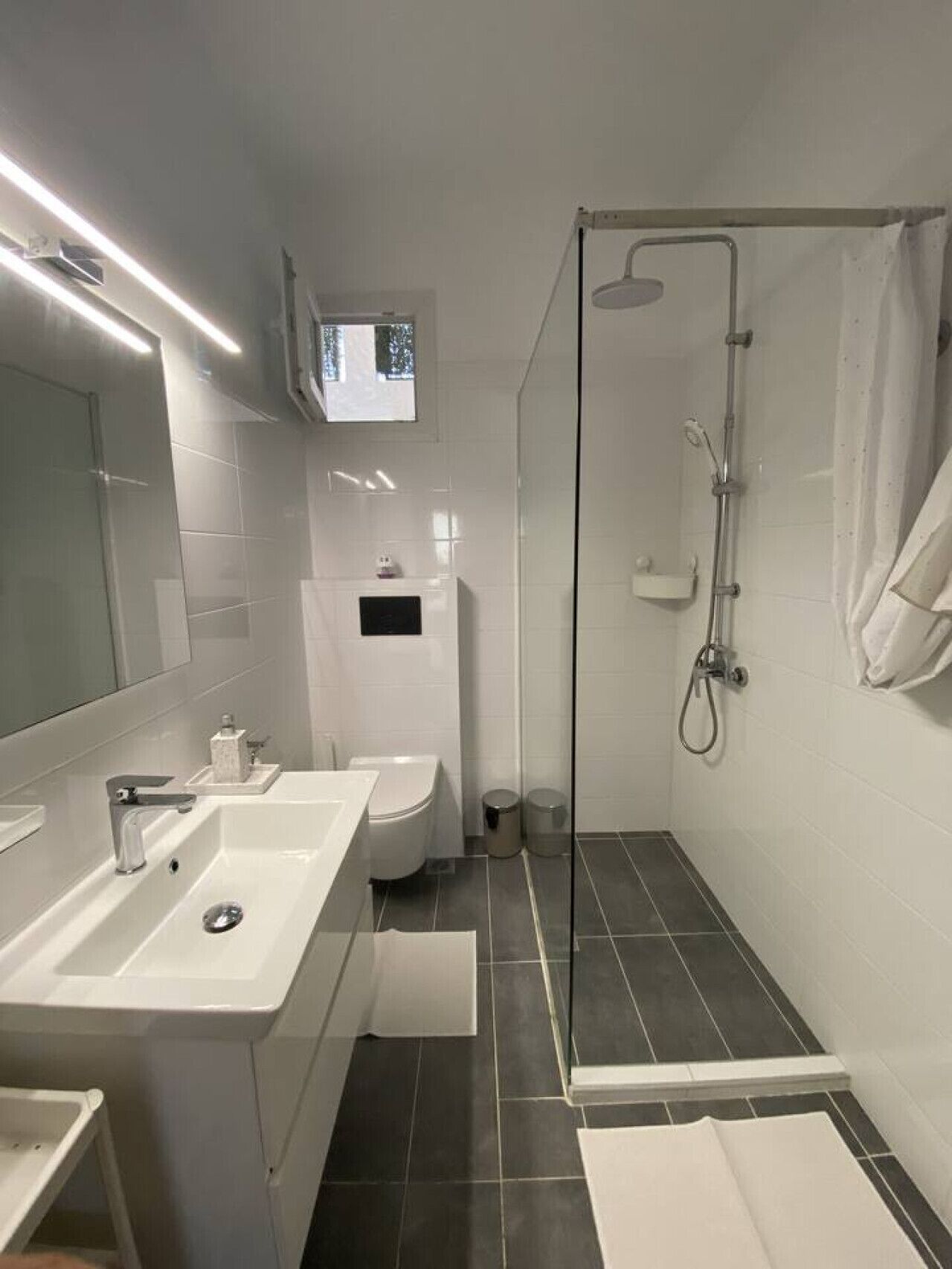 A modern bathroom with a glass-enclosed shower, a white sink, and a toilet.