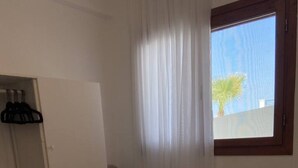 Hotellihuone, jossa on sänky, tuoli, työpöytä ja ikkuna, jossa on verhot.