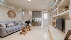 Ein modernes Wohnzimmer mit einer Couch, einem Couchtisch, einem Fernseher und einer Tür zu einem anderen Raum.