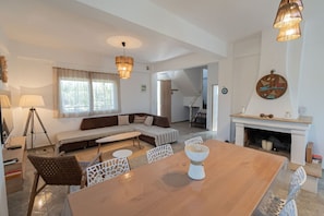 Una sala de estar moderna con sofá, mesa de comedor y chimenea.