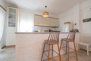 Une cuisine avec un îlot central en briques, des chaises en bois et un luminaire suspendu.