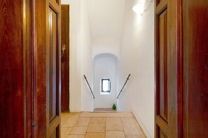 A narrow hallway with wooden doors, a small window, and a green object on the floor.