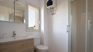 Un baño con inodoro, lavabo, espejo y ducha.