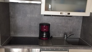 Een compacte keuken met een inbouwoven, een koffiezetapparaat en een spoelbak.