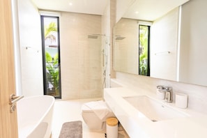 Een moderne badkamer met een bad, een douche en een toilet.