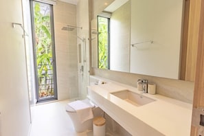 Een moderne badkamer met douche, toilet, wastafel en een grote spiegel.