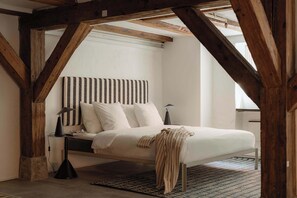 Un dormitorio con cama, mesita de noche, lámpara y ventana.