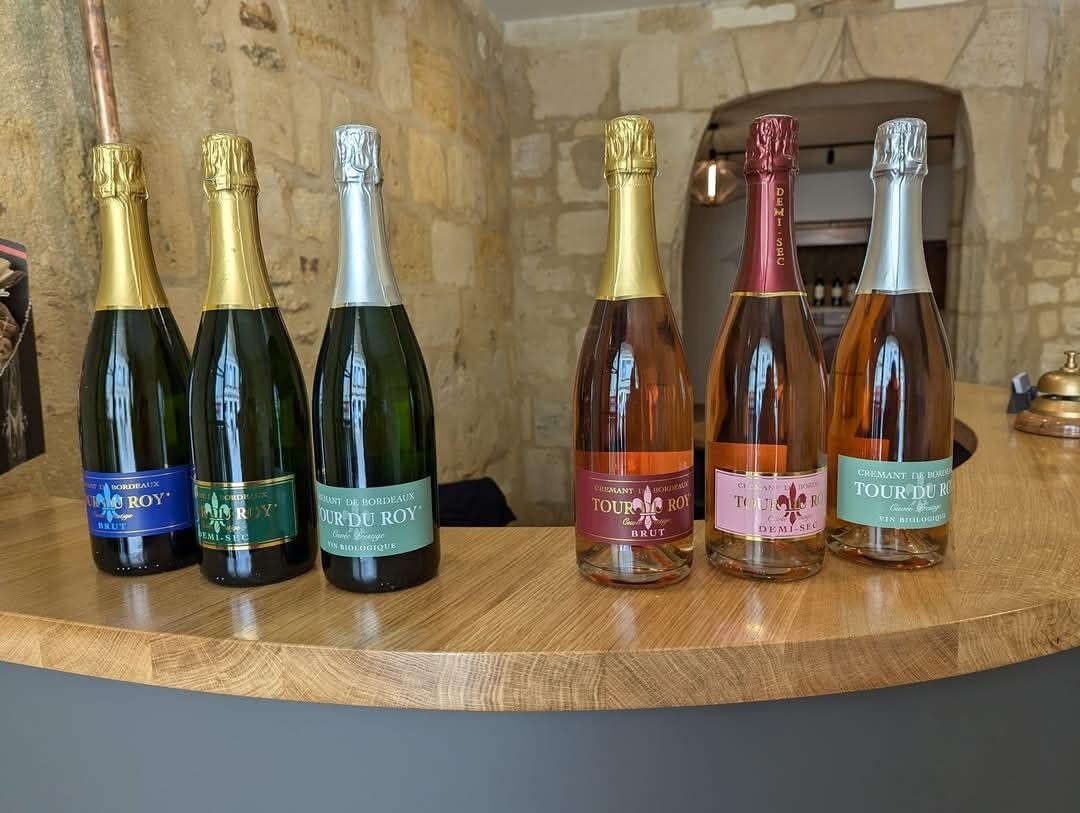 A selection of wine bottles on a wooden surface with a stone wall and fireplace in the background.