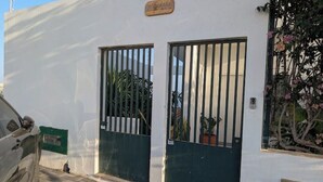 A white building with two barred doors, a green mailbox, and a potted plant. - SeafrontView · Cozy T1 Apartment - 3 (Praia)