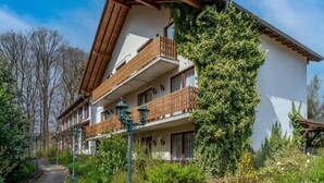 A two-story building with a sloped roof, wooden balconies, and a garden pathway. - Hotel Heiderhof by Belvilla- Double Room (Obersteinebach)