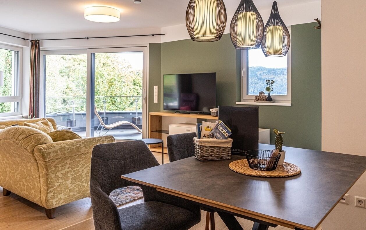 A modern living room with a sofa, dining table, chairs, a television, and decorative items.
