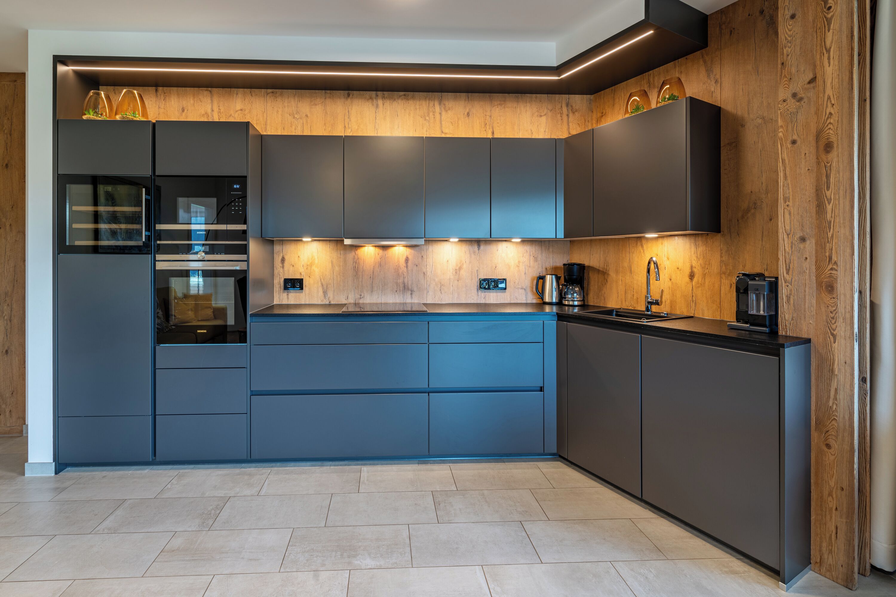 A modern kitchen with built-in appliances, a wooden accent wall, and a sleek design.