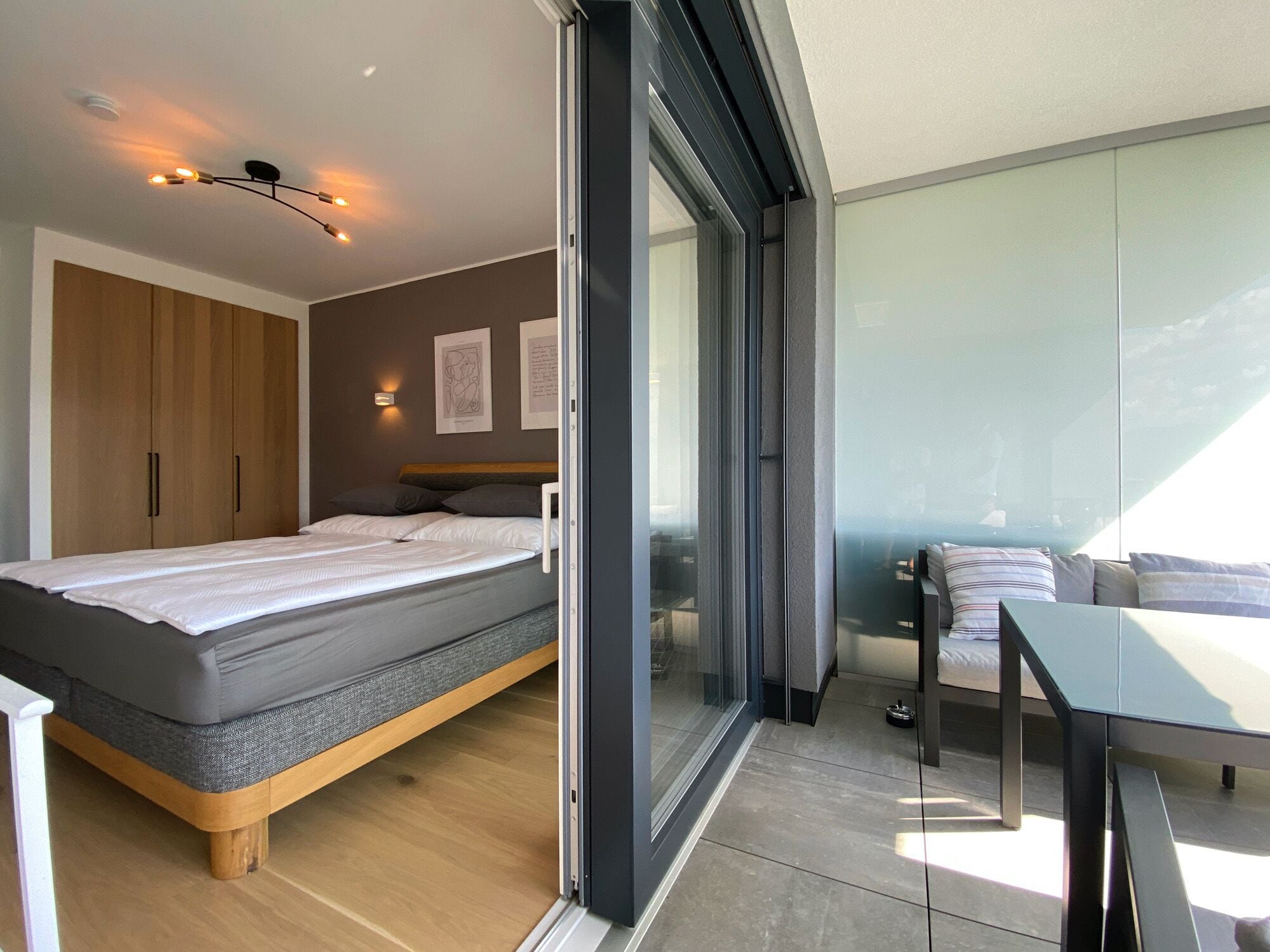 Une chambre moderne avec un lit, une armoire et un balcon équipé d’une table et de chaises.