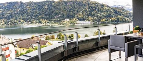 A balcony with a view of a lake and forested hills.