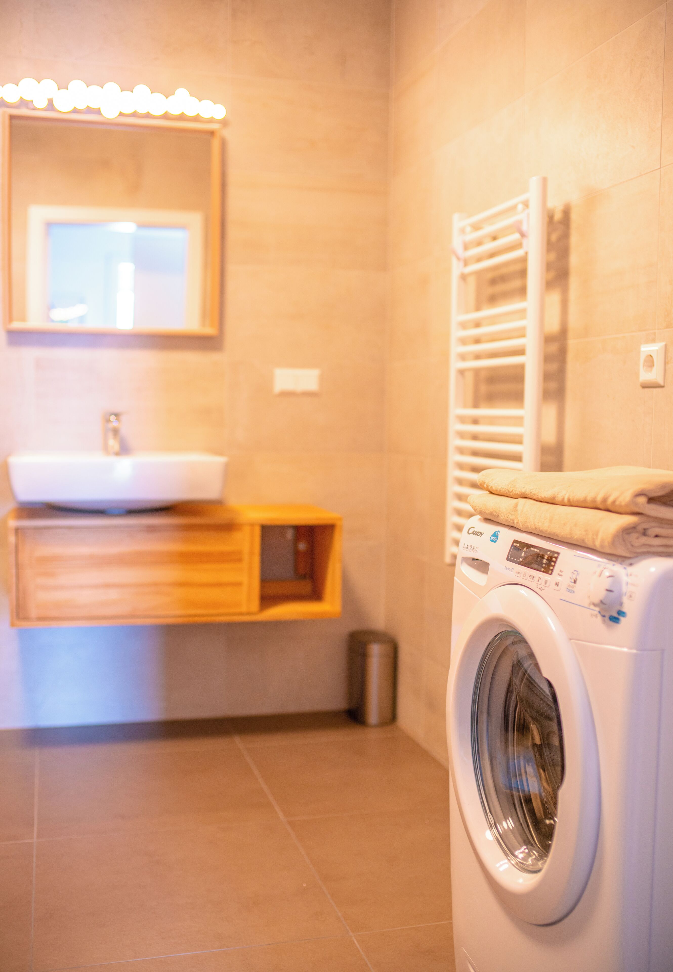 A bathroom with a sink, mirror, and a front-loading washing machine.