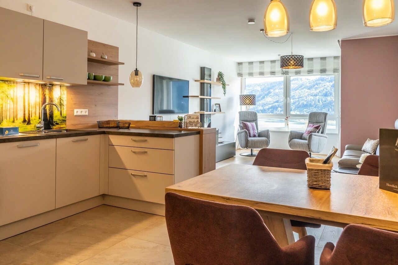 A modern kitchen with a dining area, wooden cabinets, and pendant lights.