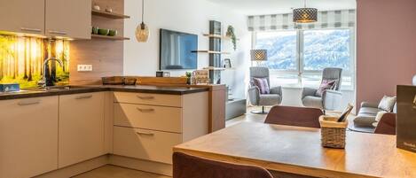 A modern kitchen with a dining area, wooden cabinets, and pendant lights.