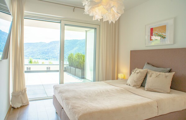 A bedroom with a large bed, a view of mountains, and a balcony. - Alpe Maritima by Ossiachersee Residences (Annenheim)