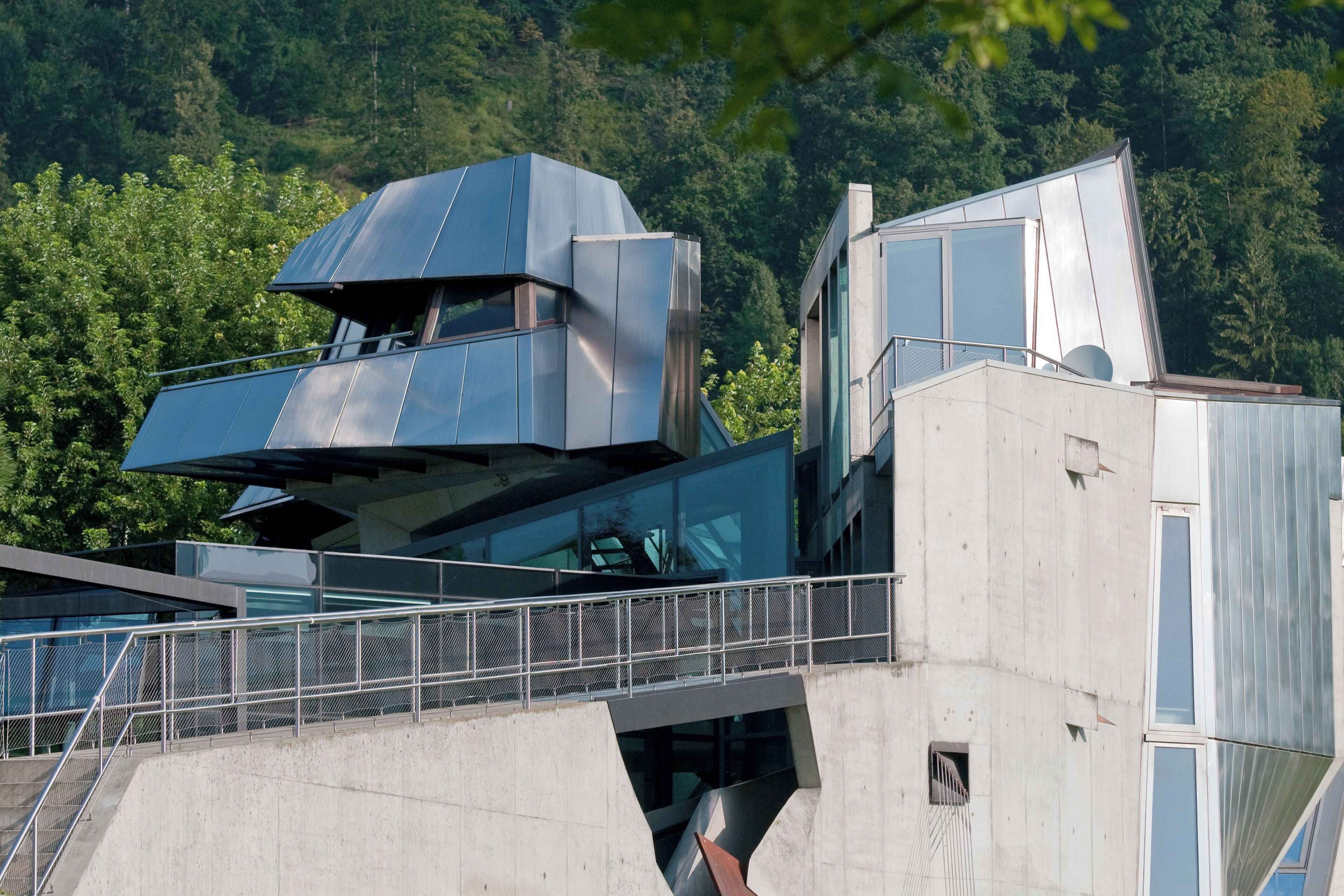 A modern building with a unique architectural design, featuring a prominent overhanging structure and a glass facade.