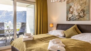 Ein Hotelzimmer mit Bett, Schreibtisch und Stuhl, einem Fenster mit Blick auf einen Berg und einem Bild an der Wand.