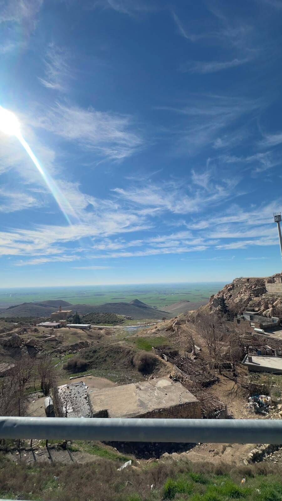 A landscape view with a clear sky, distant hills, and a structure on the right.