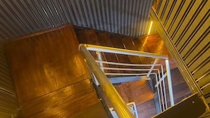 Eine Treppe mit Holzboden und Metallgeländern, die zu einer Ebene hinabführt.