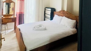 Ein Hotelzimmer mit einem hölzernen Bett, einem Schreibtisch, einem Stuhl und einem Fenster mit Vorhängen.