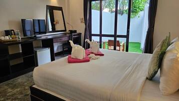 A hotel room with a bed, a desk, a chair, a TV, and a view of a garden.