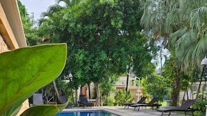 A swimming pool with tiled flooring, surrounded by lounge chairs and potted plants. - Fishermans Village Samui Yoga Retreat (Koh Samui)