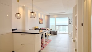 Een moderne woonkamer met een eethoek, een keukenbar en een balkon met uitzicht.