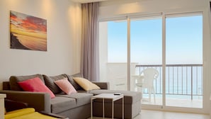 Een moderne woonkamer met een bank, een bijzettafeltje en een balkon met uitzicht op zee.