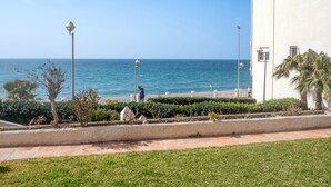 A coastal view with a white building, a paved walkway, and a person walking. - Arce I 26 by Casasol (Nerja)