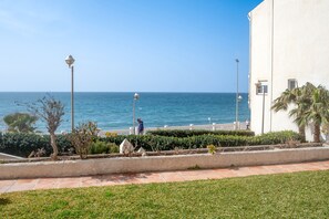 A coastal view with a white building, a paved walkway, and a person walking. - Arce I 26 by Casasol (Nerja)