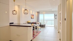 A modern living room with a dining area, a kitchen counter, and a balcony with a view. - Arce I 26 by Casasol (Nerja)
