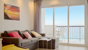 A modern living room with a sofa, a small table, and a balcony with a view of the sea. - Arce I 26 by Casasol (Nerja)