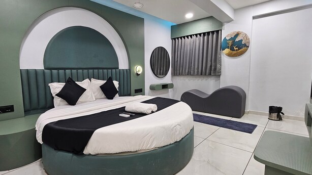 Una habitación de hotel moderna con una cama curva, un tocador y una pequeña zona de estar.