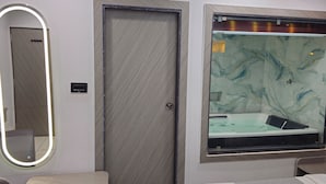 Un baño con espejo, puerta y pared de mármol con bañera.