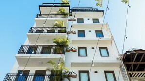 Un edificio de varios pisos con balcones, ventanas y algo de vegetación.