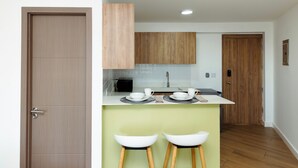 Una cocina moderna con armarios de madera, una encimera blanca y dos taburetes blancos.