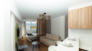 Un espace de vie moderne et compact, comprenant un canapé, une table à manger et un petit coin cuisine.