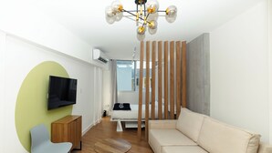 Un salon moderne avec un canapé, un téléviseur, un meuble en bois et une petite table.