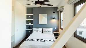 A bedroom with a bed, ceiling fan, bedside table, lamp, and a window. - Located in the heart of Casco Viejo’s nightlife 🎶🌃<br>Steps from bars and nightclubs, perfect for those who want a lively vibe 🍸🕺<br>There is nighttime noise due to the nightclub area 🔊✨ (Casco viejo)