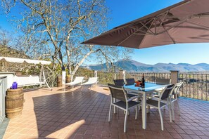 Um pátio com mesa e cadeiras, uma pérgola e vista para montanhas.