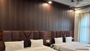Une chambre d’hôtel avec deux lits, des murs lambrissés, un luminaire au plafond et une fenêtre avec des rideaux.
