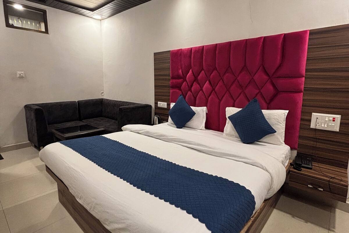 Een moderne slaapkamer met een groot bed, een donkere bank, een houten hoofdbord en een plafondventilator.