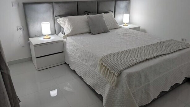 A neatly arranged bedroom with a bed, two bedside tables, and a nightstand. - Modern & Stylish 1BR Apt | Cidadela | Ground Floor (Praia)