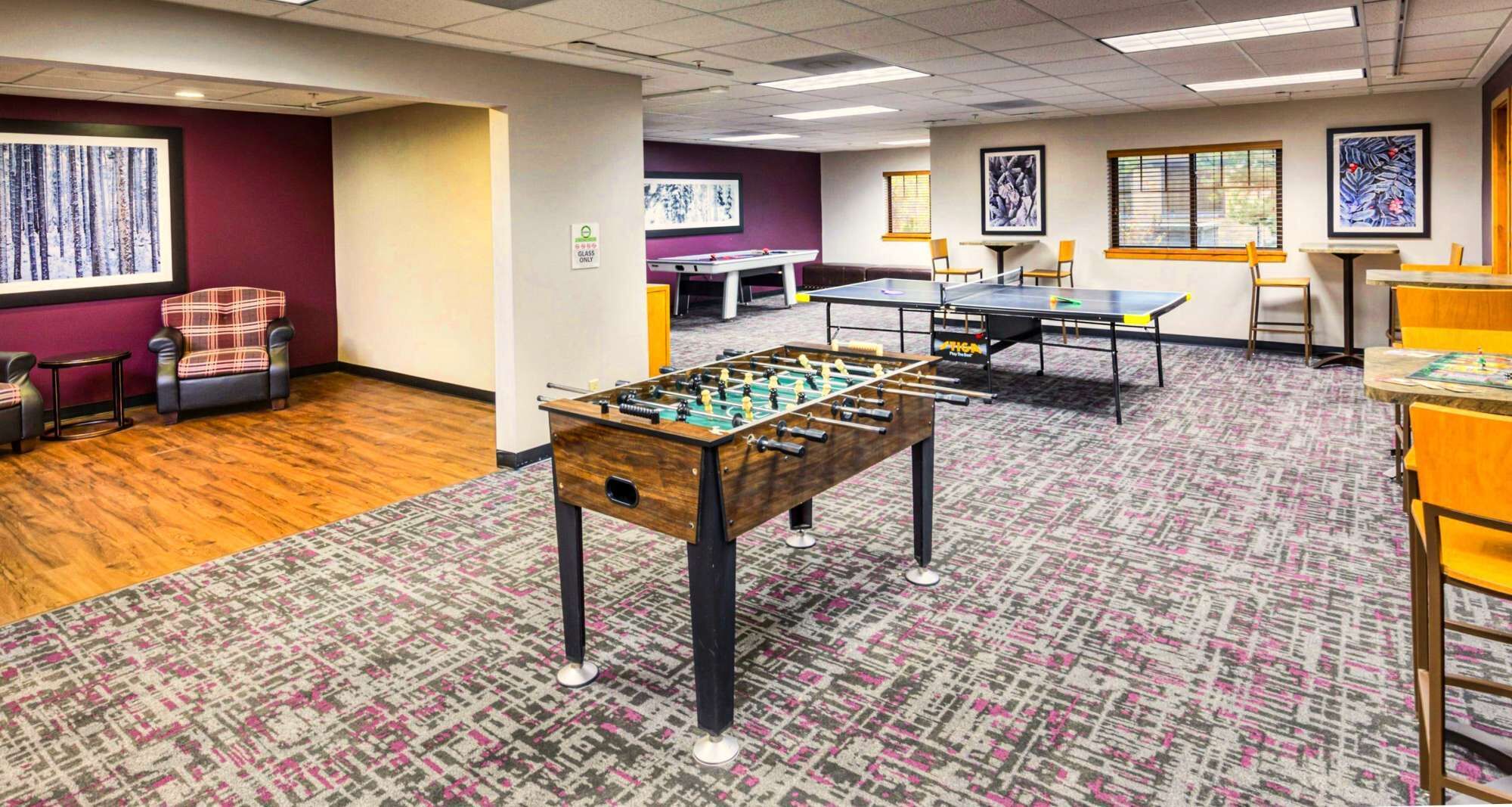 Een kamer met een tafelvoetbaltafel, een pooltafel en een pingpongtafel.