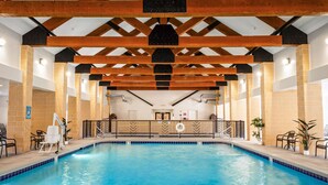 Ein Hallenbad mit Holzbalkendecke, gefliesten Wänden und einem Poolbereich mit Stühlen und einem Rettungsring.